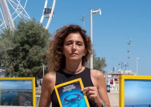 Femme avec magazine National Geographic sur la plage.