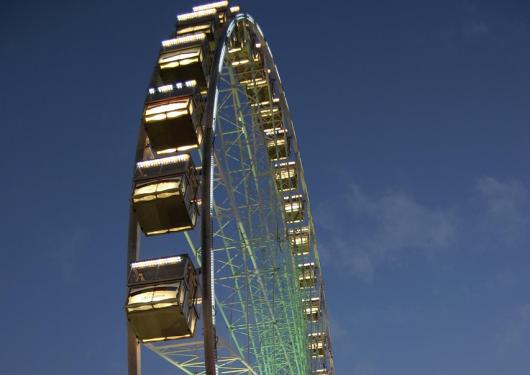 Illuminated Ferris wheel at dusk with dark blue sky.